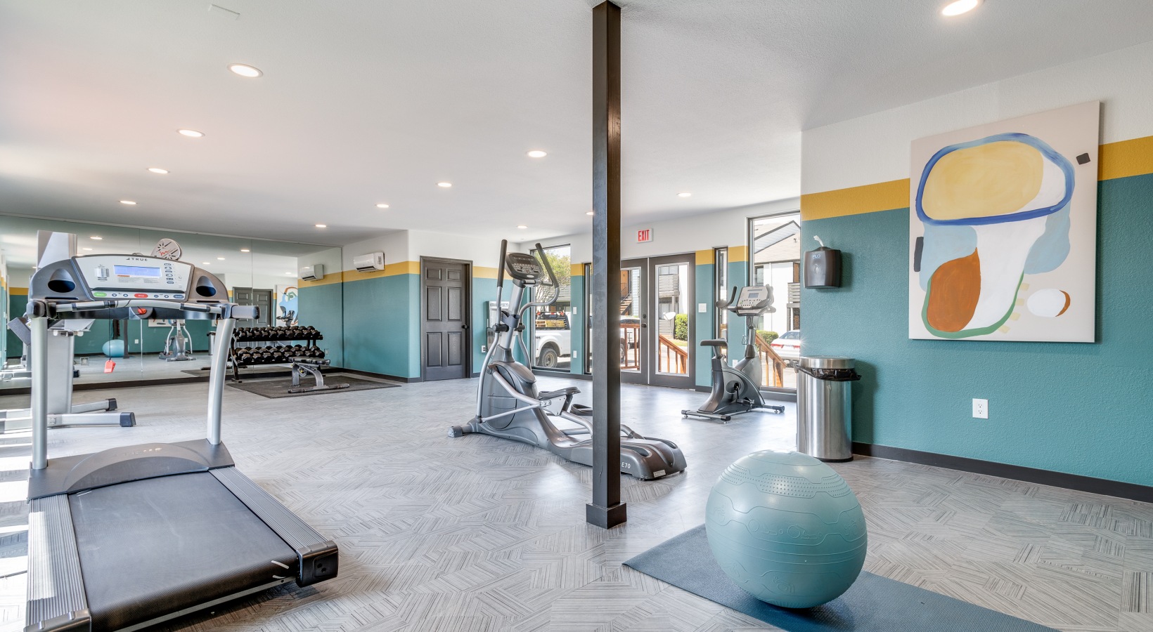 a gym room with exercise equipment and a large painting at The Melville