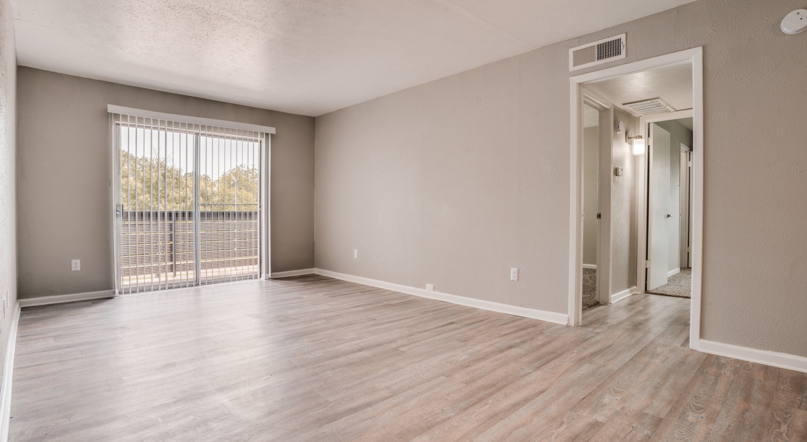 an empty room with hardwood floors and sliding glass door at The Melville